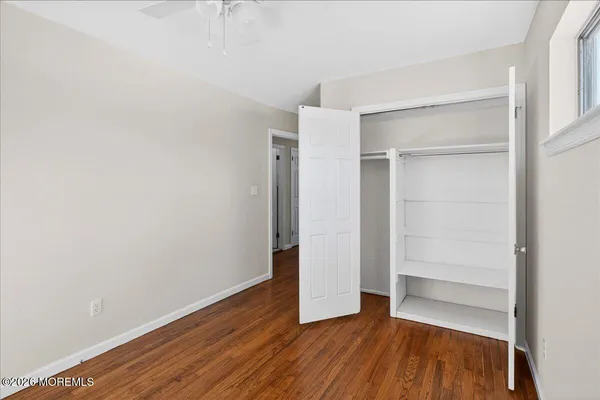 a view of an empty room with closet and wooden floor