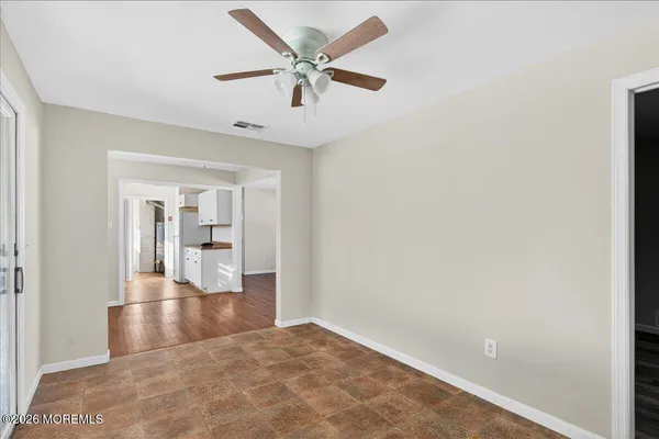 an empty room with wooden floor and ceiling fan