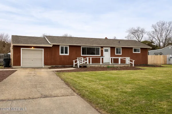 a front view of house with yard and trees in the background