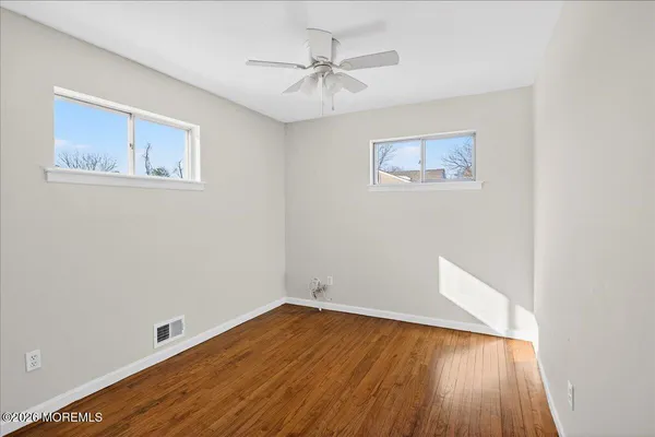 an empty room with wooden floor and a ceiling fan