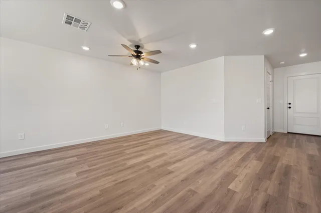 a view of empty room with wooden floor and ceiling fan