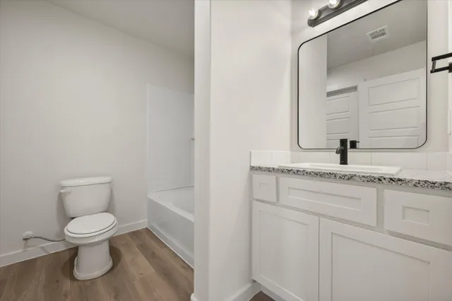 a bathroom with a granite countertop toilet sink and mirror