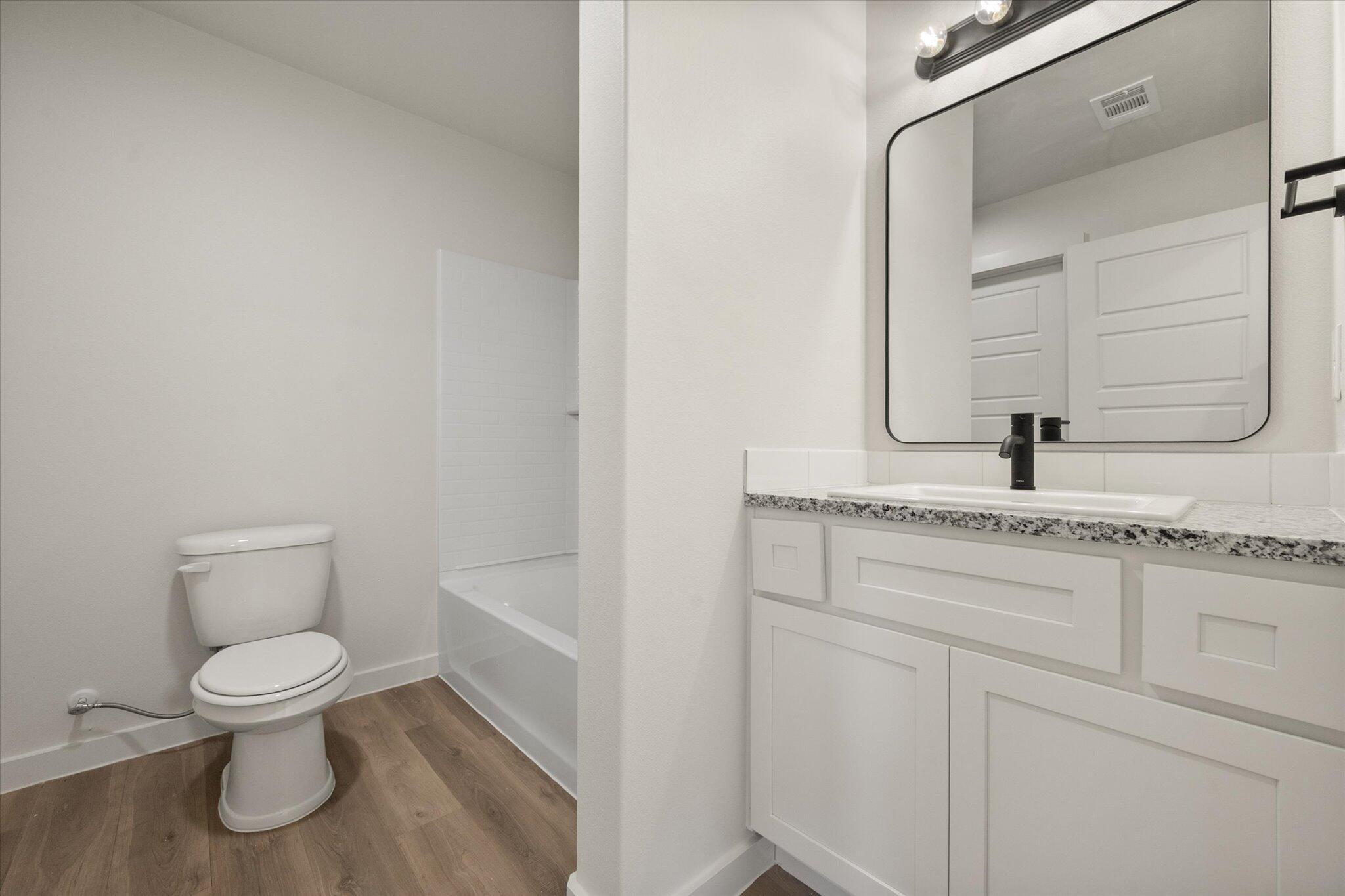 8316 24th Street Lubbock, TX 79407 - Photo 17 of 22 a bathroom with a granite countertop toilet sink and mirror