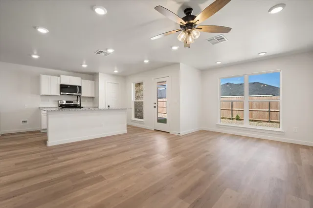 a view of a kitchen with furniture a ceiling fan and wooden floor