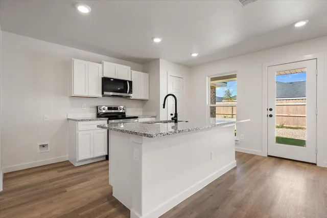 a kitchen with stainless steel appliances granite countertop a stove a sink and a microwave