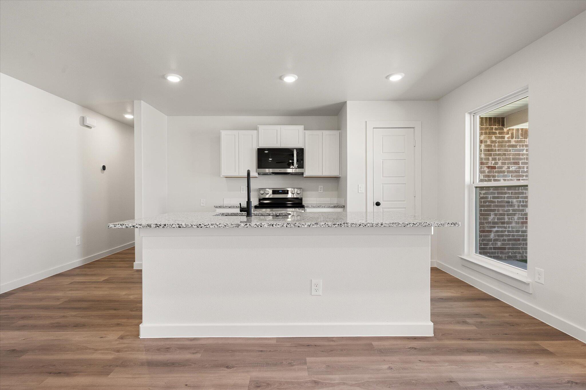 8316 24th Street Lubbock, TX 79407 - Photo 8 of 22 a view of kitchen with stainless steel appliances granite countertop a stove a sink a refrigerator and white cabinets with wooden floor