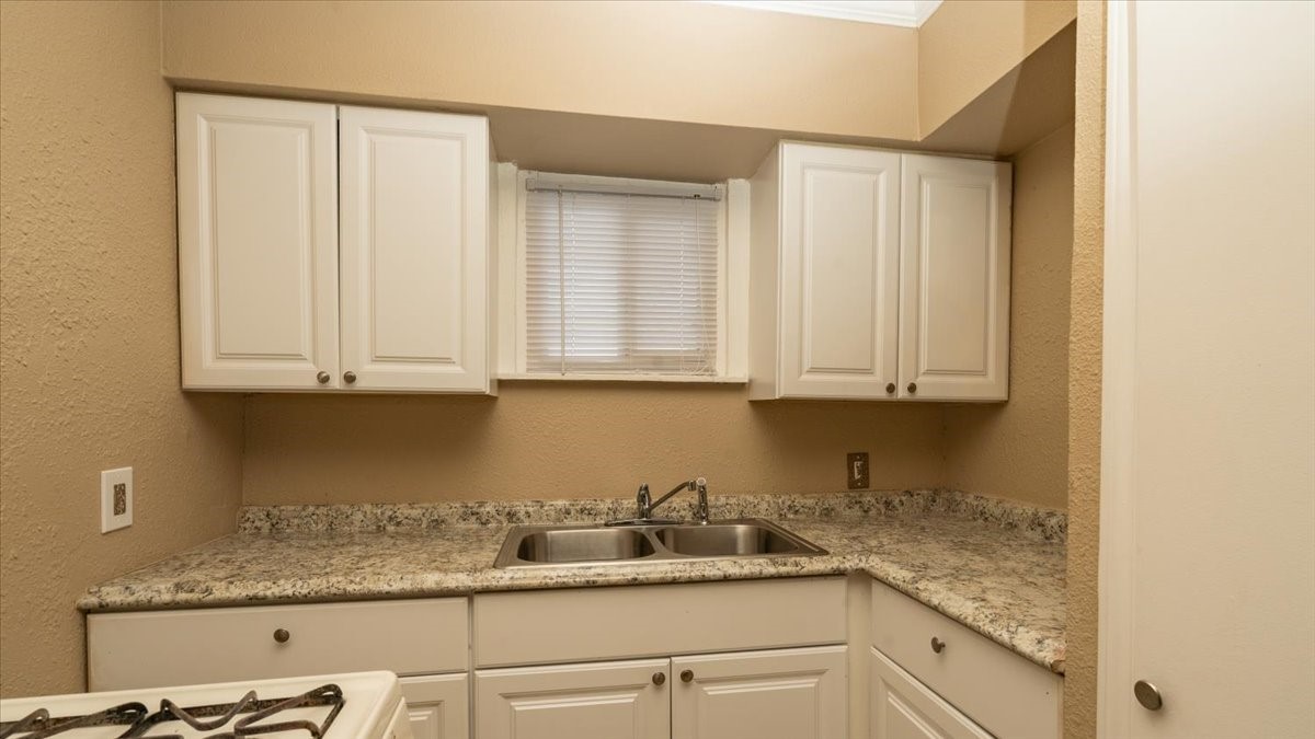 3045 Golfcrest Boulevard, Unit 10 Houston, TX 77087 - Photo 2 of 7 a kitchen with granite countertop white cabinets and sink