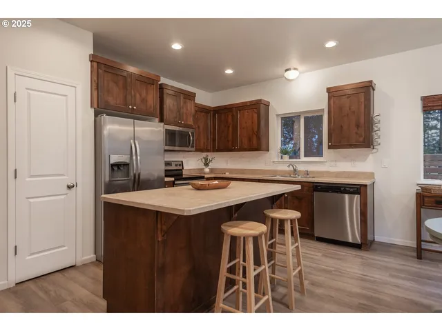 a kitchen with stainless steel appliances granite countertop a table chairs sink refrigerator and microwave