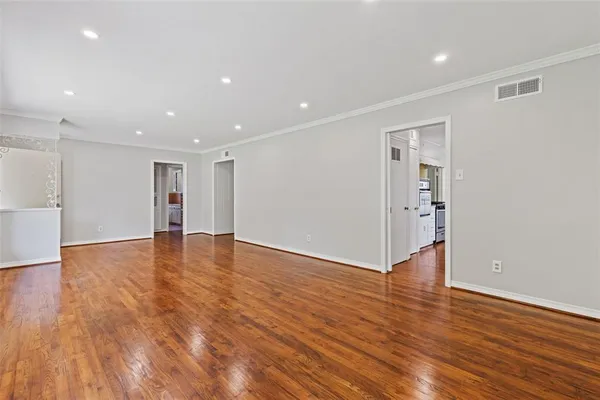a view of an empty room with wooden floor and closet