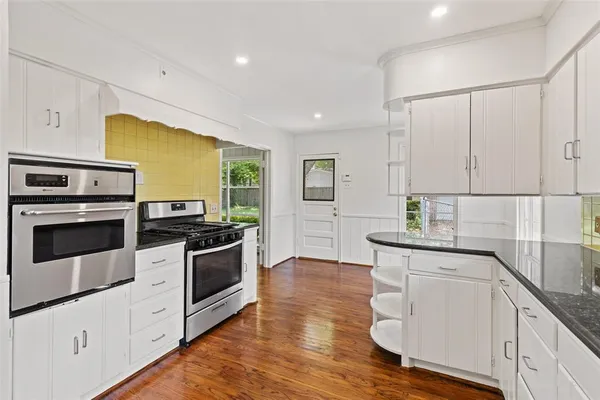 a kitchen with granite countertop white cabinets and white appliances