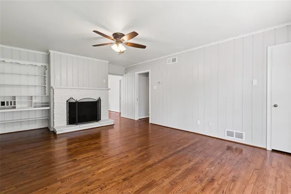 a view of a livingroom with wooden floor a ceiling fan and a fireplace