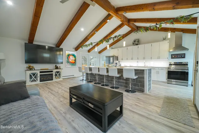 a living room with stainless steel appliances kitchen island furniture and a flat screen tv