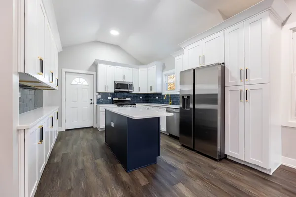 a kitchen with stainless steel appliances a refrigerator a sink and wooden floors