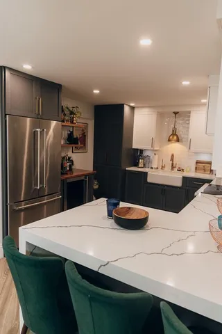 a kitchen with stainless steel appliances granite countertop a refrigerator and a dining table with wooden floor