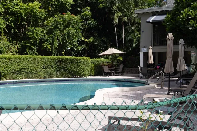 a view of a table and chairs under an umbrella in front of house