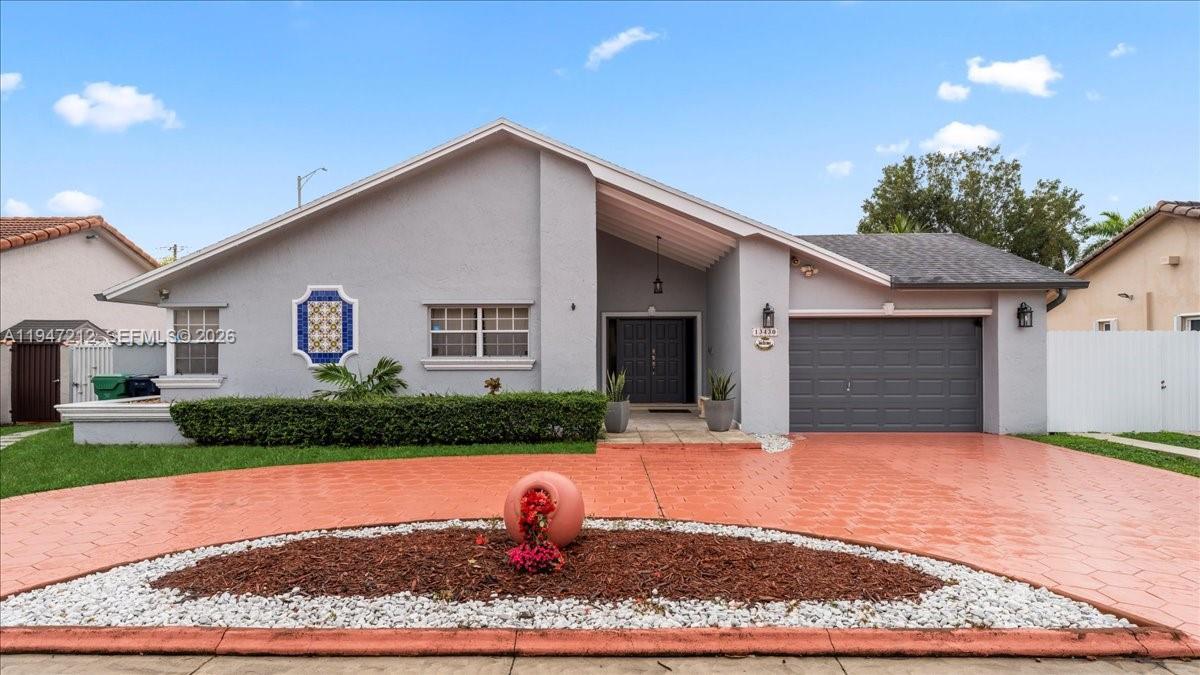 13430 Southwest 25th Street Miami, FL 33175 - Photo 2 of 49 a front view of a house with a yard and garage