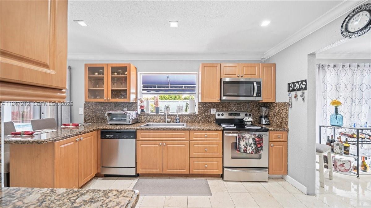 13430 Southwest 25th Street Miami, FL 33175 - Photo 25 of 49 a kitchen with stainless steel appliances granite countertop a stove top oven a sink a counter top space and cabinets