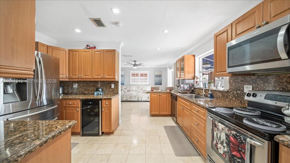 13430 Southwest 25th Street Miami, FL 33175 - Photo 27 of 49 a kitchen with stainless steel appliances granite countertop a stove top oven a sink a counter space and cabinets