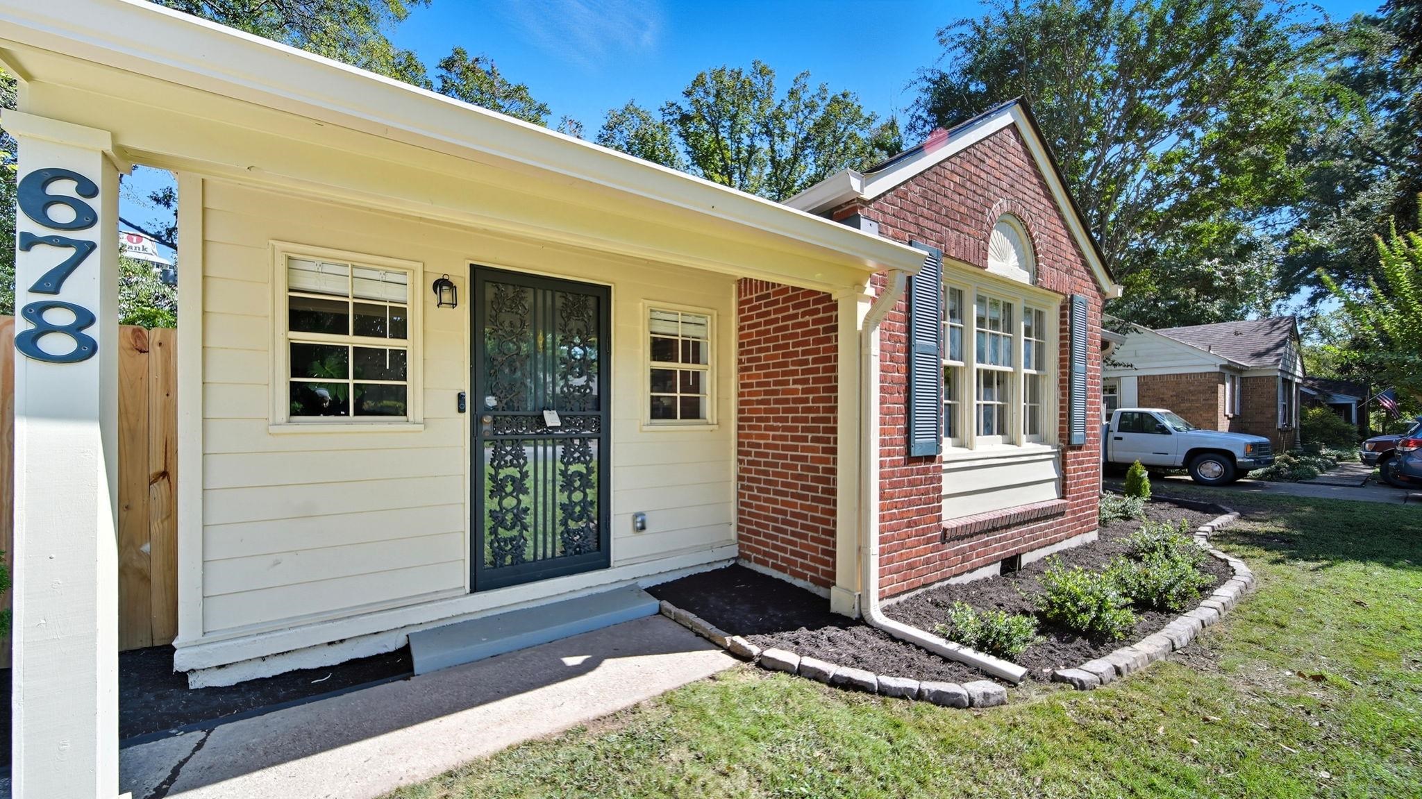 678 Moss Road Memphis, TN 38117 - Photo 17 of 33 Doorway to property with brick siding, covered porch, and a yard