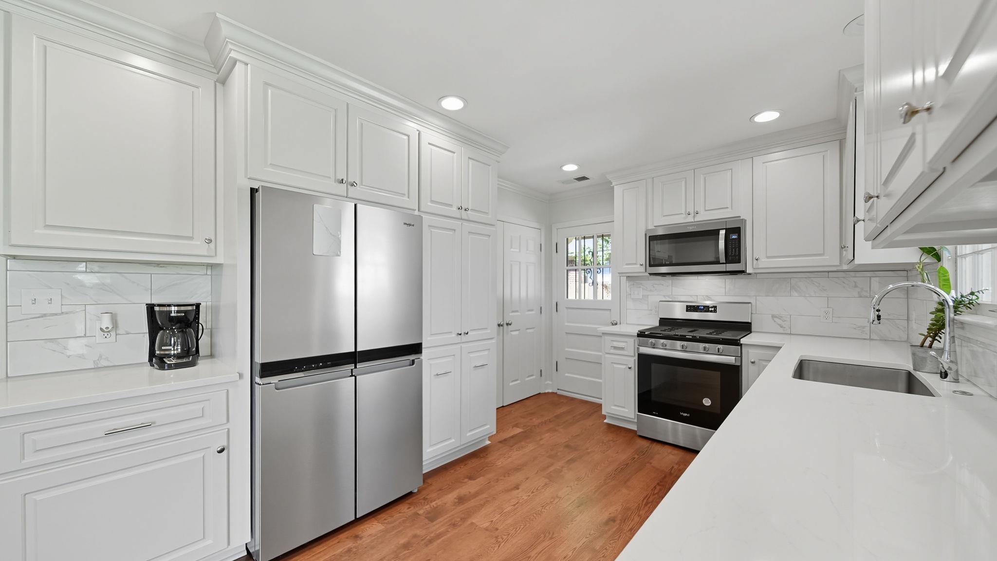 678 Moss Road Memphis, TN 38117 - Photo 24 of 33 Kitchen featuring appliances with stainless steel finishes, white cabinets, tasteful backsplash, light stone counters, and light wood finished floors
