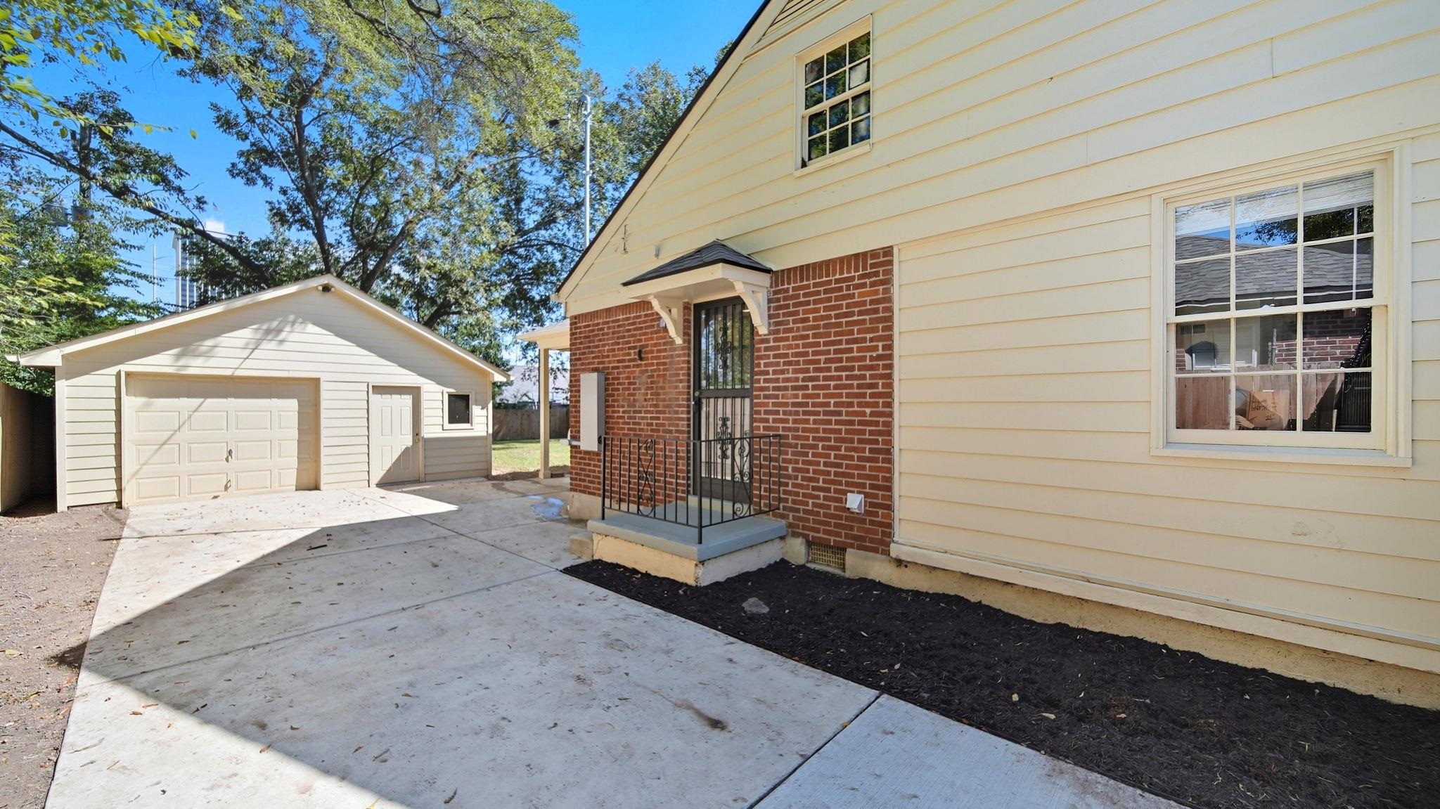 678 Moss Road Memphis, TN 38117 - Photo 32 of 33 View of side of property featuring an outdoor structure, concrete driveway, a garage, and brick siding