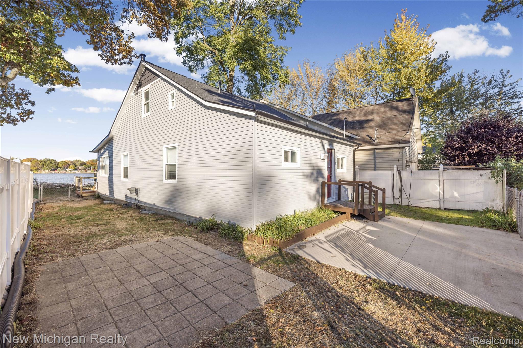 8665 Cooley Lake Road Commerce Township, MI 48382 - Photo 6 of 52 View of side of home featuring a fenced backyard, a water view, and a patio area