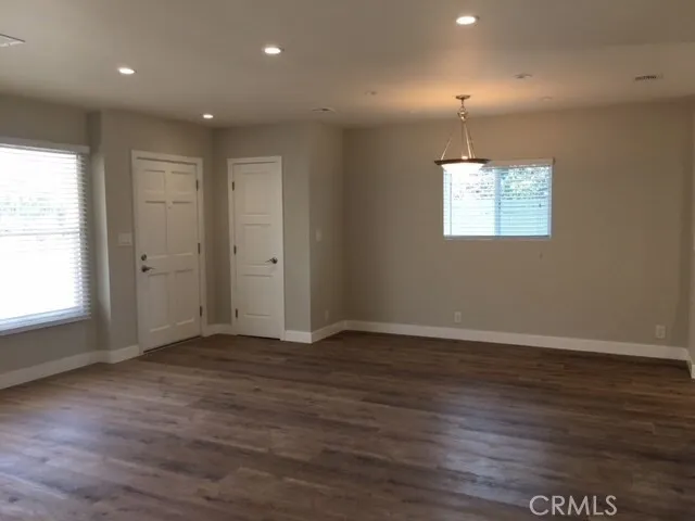 an empty room with wooden floor cabinet and windows