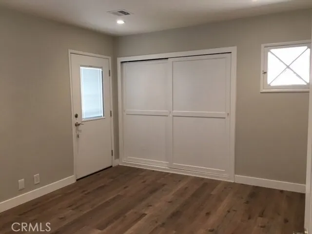 an empty room with wooden floor closet and windows