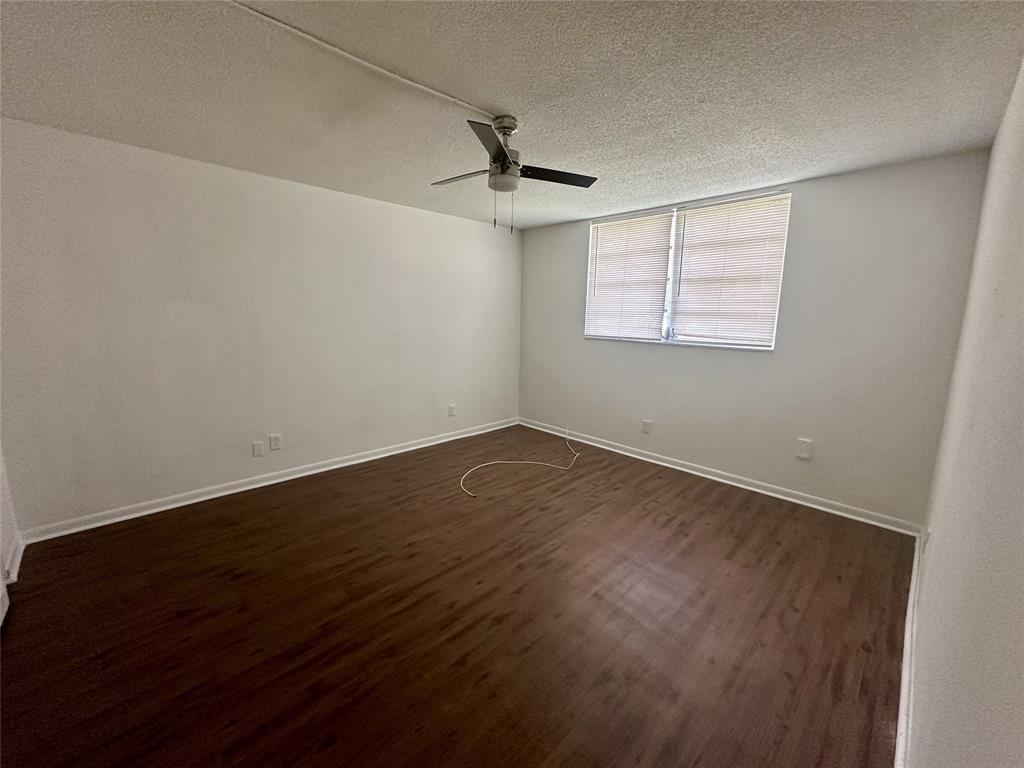 5980 Northwest 64th Avenue, Unit 112 Tamarac, FL 33319 - Photo 6 of 13 an empty room with wooden floor ceiling fan and windows