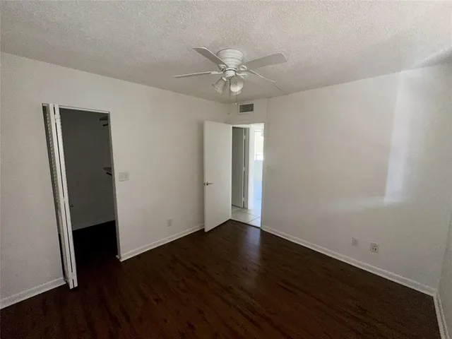 an empty room with wooden floor fan and windows