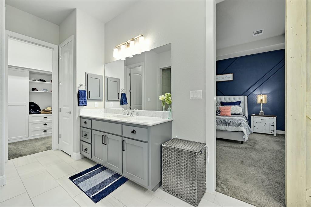629 Germander Road Leander, TX 78641 - Photo 15 of 32 Marble-topped double vanity in a well-lit bathroom, complemented by an adjoining organized closet and bedroom.