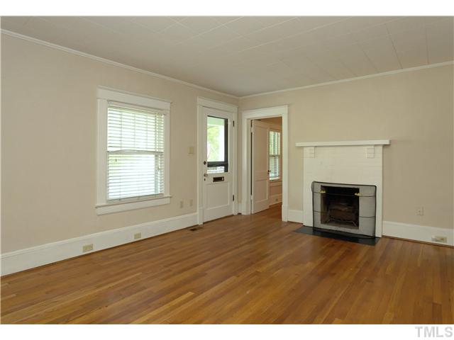 124 Hudson Street Raleigh, NC 27608 - Photo 4 of 19 an empty room with wooden floor fireplace and windows
