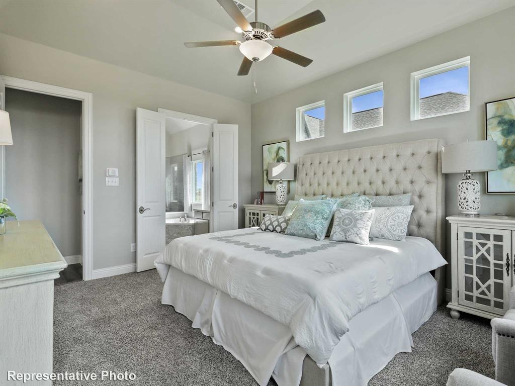 1143 Rothland Lane Red Oak, TX 75154 - Photo 8 of 18 Carpeted bedroom featuring a ceiling fan with integrated lighting, three transom windows, and double doors opening to a bathroom with a soaking tub