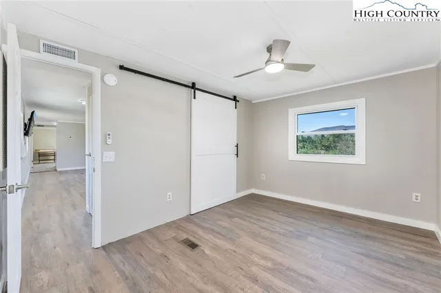 a view of an empty room with wooden floor and a ceiling fan