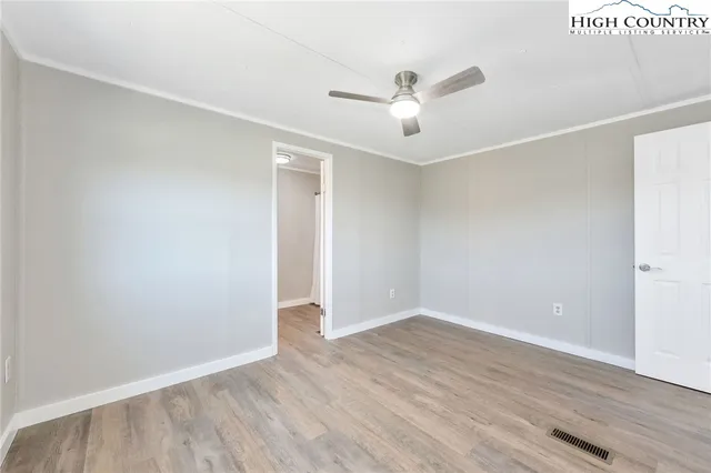 an empty room with wooden floor and ceiling fan