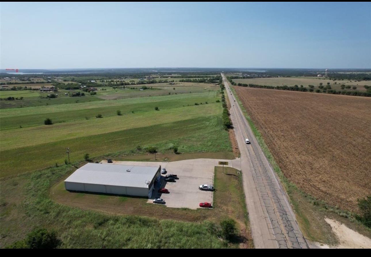 11609 Highway 36 Temple, TX 76502 - Photo 2 of 6 An aerial perspective reveals a vast landscape with a large commercial building, ample parking, and an adjacent long, paved road.