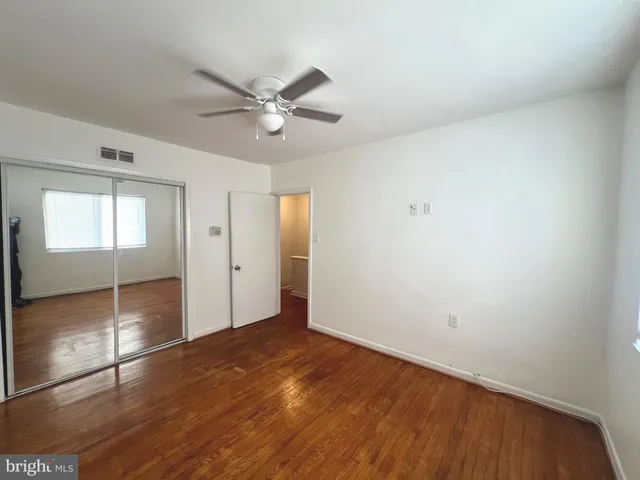 an empty room with wooden floor fan and windows