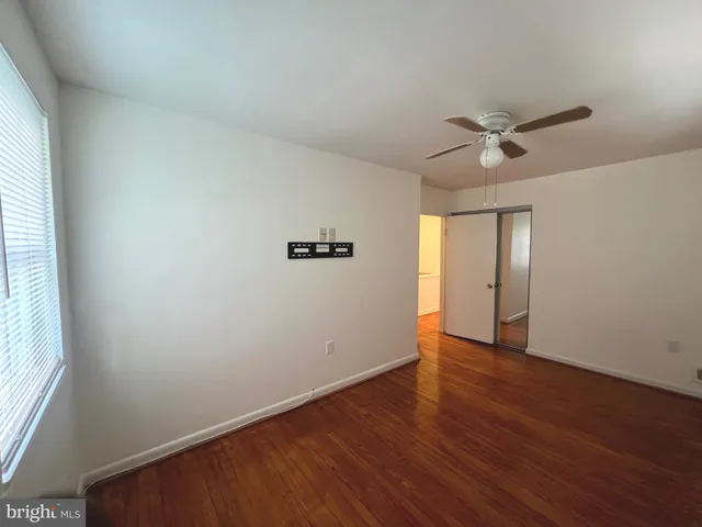 an empty room with wooden floor chandelier fan and windows