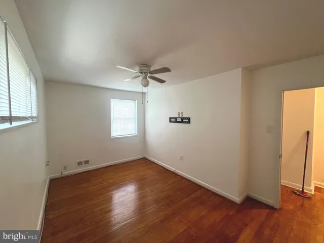an empty room with wooden floor closet and windows