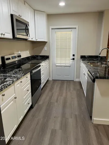 a kitchen with granite countertop wooden floors and white stainless steel appliances