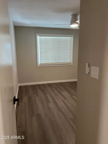a view of an empty room with a window and wooden floor