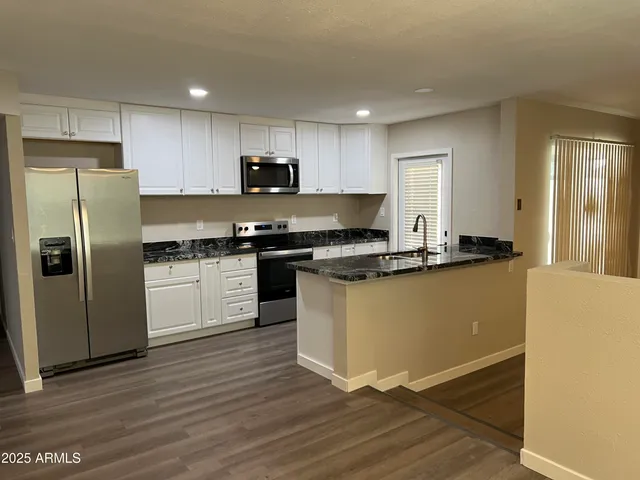 a kitchen with granite countertop a refrigerator stove top oven and sink