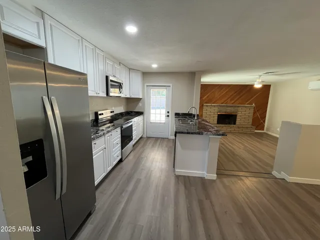 a kitchen with stainless steel appliances granite countertop a refrigerator a stove top oven a sink dishwasher and wooden floor