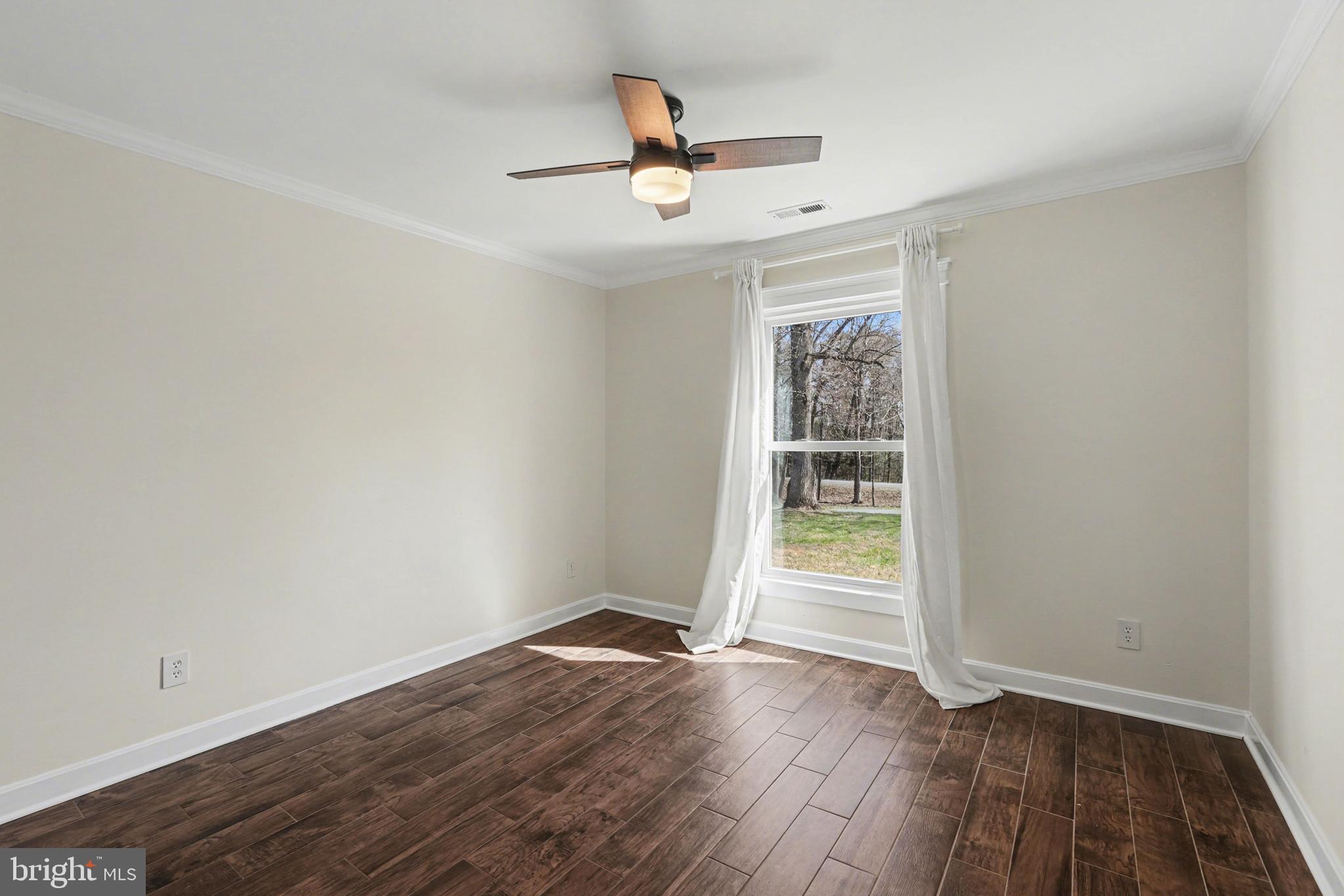 11080 Dutch Hollow Road Culpeper, VA 22701 - Photo 22 of 28 an empty room with wooden floor ceiling fan and windows