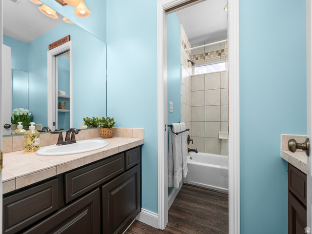 6849 North Black Powder Road Mountain Green, UT 84050 - Photo 20 of 43 Bathroom featuring a dark wood-finish vanity with an integrated basin sink, tiled countertop, and bronze-finish hardware