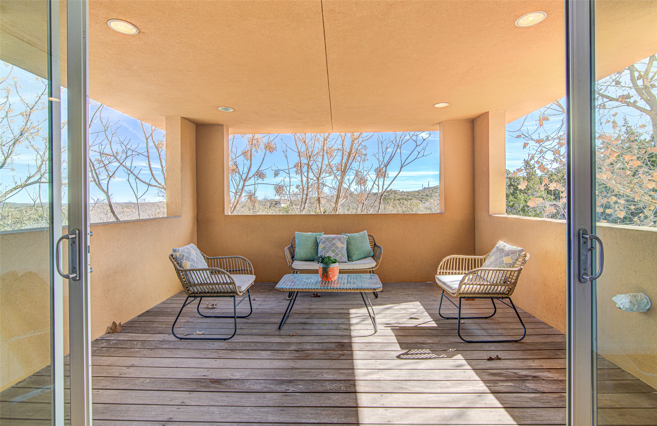 9707 Timber Ridge Pass Austin, TX 78733 - Photo 9 of 18 Sliding glass doors open onto a covered wood deck overlooking serene natural surroundings.