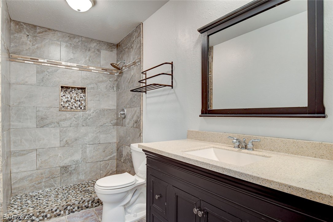 1810 Pinto Road Henderson, NV 89002 - Photo 34 of 53 A refined bathroom features a spacious walk-in shower with intricate tile work and a sleek vanity.