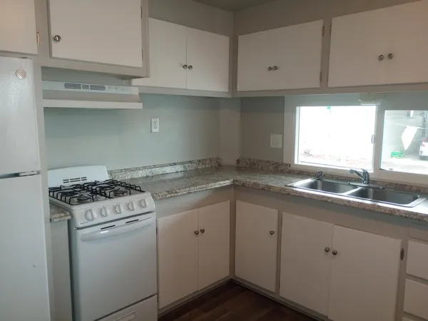 a kitchen with cabinets appliances a sink and a window