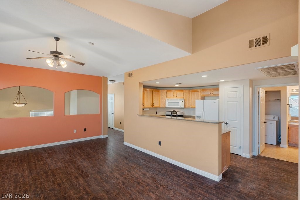 10001 Peace Way, Unit 2311 Las Vegas, NV 89147 - Photo 33 of 35 Kitchen featuring a peninsula, white appliances, dark wood-style flooring, washer / dryer, and open floor plan