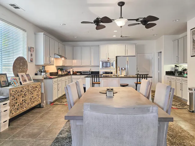 a kitchen with stainless steel appliances granite countertop a table chairs and a refrigerator